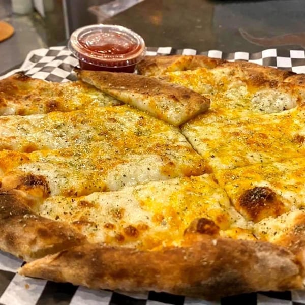 Back Alley Pizza's cheesy garlic bread, cut into strips, with a side of marinara sauce.